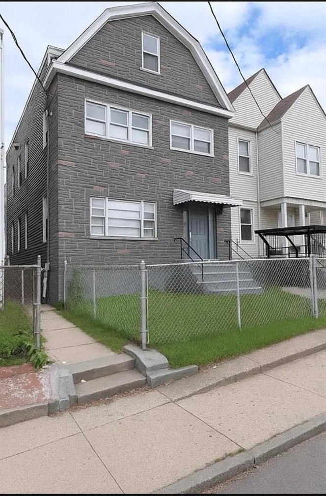 Front exterior of the gray house with entry steps and a fenced lawn